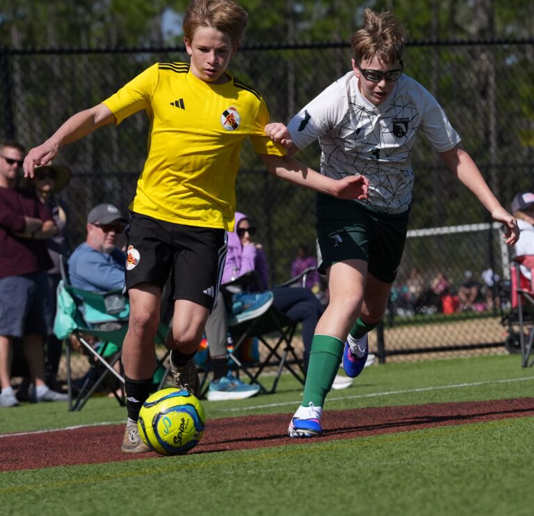 Two soccer players fight for the ball at full sprint